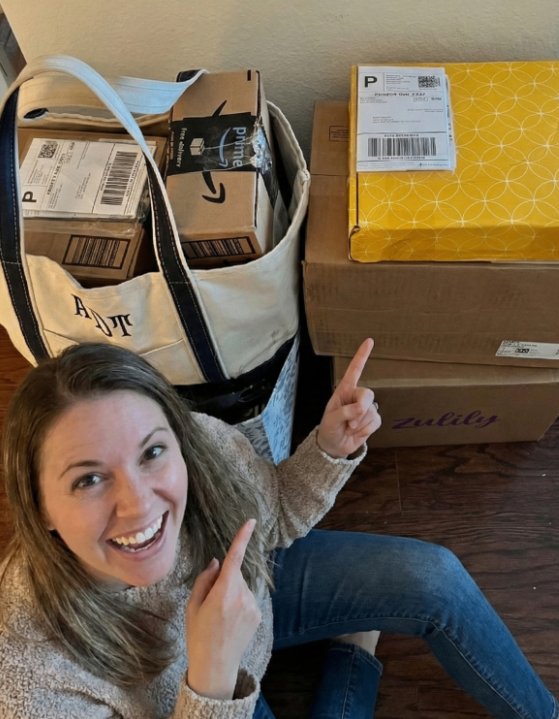 Happy user pointing to a bag and stack of shipping boxes ready for dispatch through the DropFlow platform.
