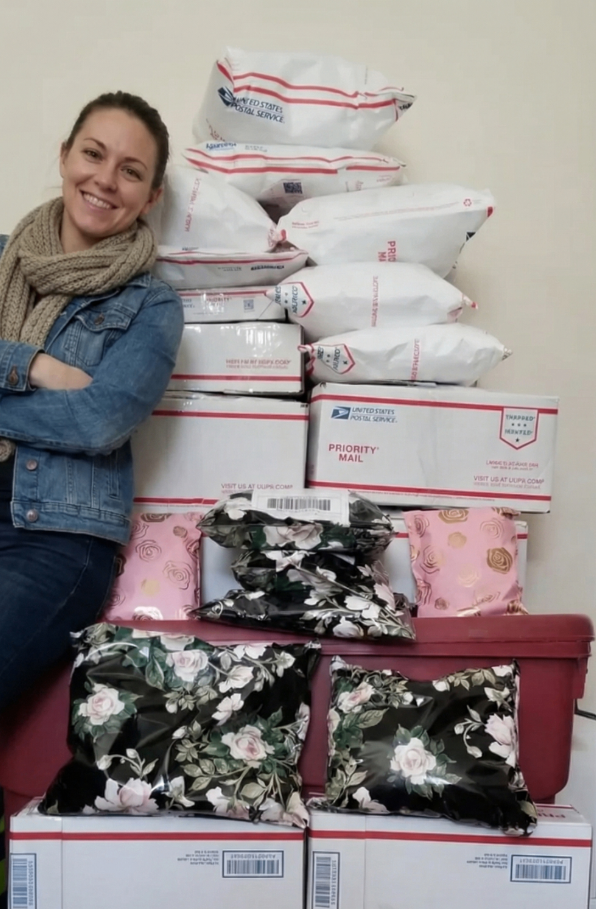 Smiling DropFlow user standing next to a large stack of shipping boxes and packages ready for customer delivery.
