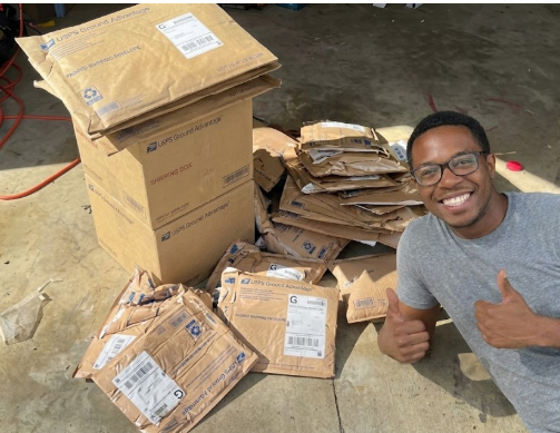 Successful seller giving a thumbs up next to a large pile of brown shipping mailers and boxes fulfilled via DropFlow.